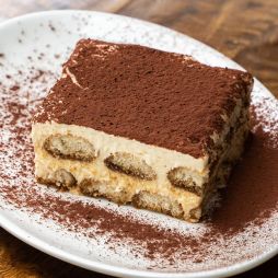 A piece of tiramisu on a white plate.
