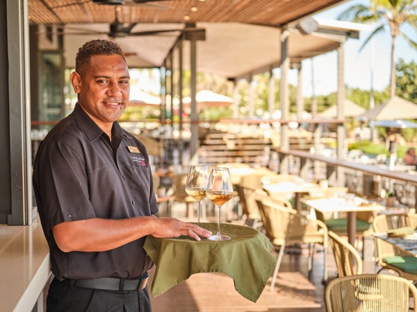 a waiter smiling while serving at Cable Beach Club