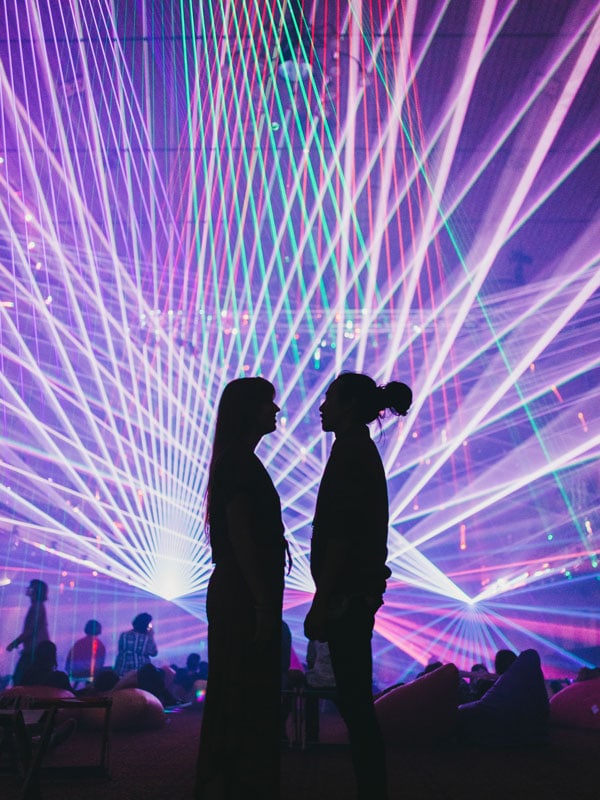 two people facing each other with colourful lights as a backdrop at MONA FOMA