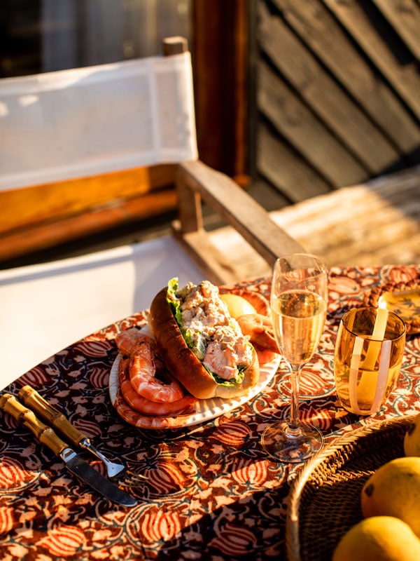 prawn sandwich on a plate with sparkling wines on the table