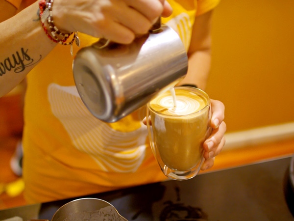 a barista pouring coffee into the glass at Mad About Coffee