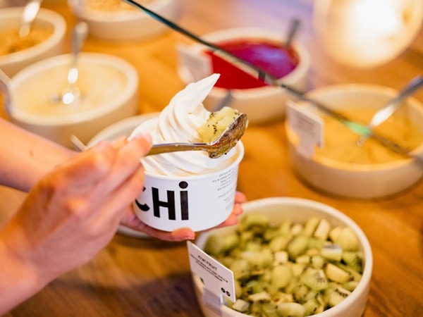 a hand picking toppings for yoghurt at Yo-Chi, Adelaide SA