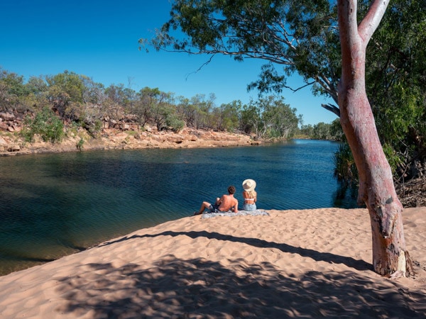 a couple sitting on the white-sand beach at Warla Gorge