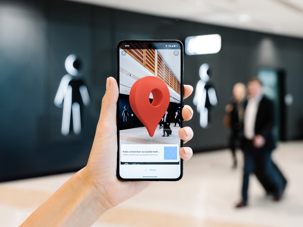 Google Maps Indoor Live View phone with destination pin at wheelchair accessible bathroom