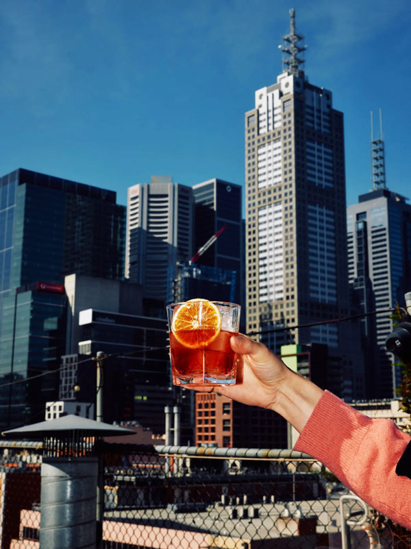 a hand holding up a cocktail glass at Rooftop Bar, Melbourne CBD