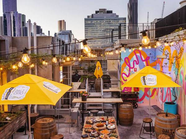 the open-air bar at Rooftop at QT with fairy lights and vibrant yellow umbrellas