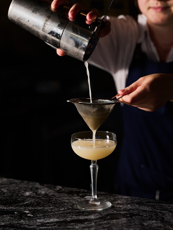 pouring a cocktail drink into a glass at Midnight Bar