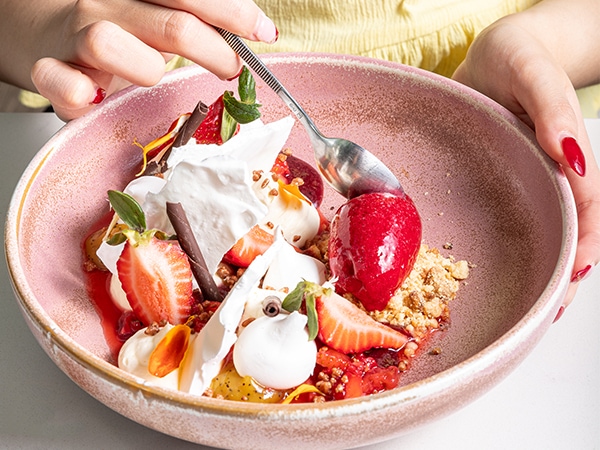 A woman using a spoon to dig into a bowl of strawberry Eton mess at Goldfinch.