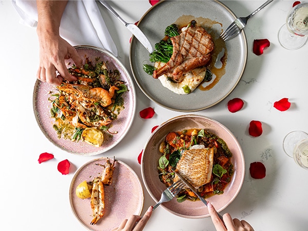 Plates of food on a table scattered with petals.