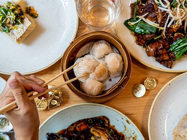 Person using chopsticks to enjoy dumplings at Harvest Buffet at the Star Casino Sydney.