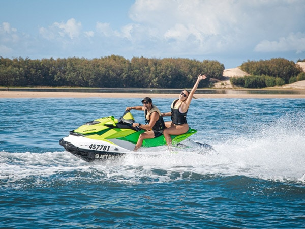 a couple riding a Jet ski across Stradbroke Island, Qld