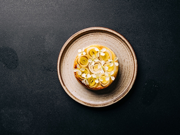a very pretty fermented leek Danish served on an earthy plate on a charcoal table.