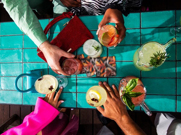 hands holding cocktails on the table at Rooftop at QT, Perth