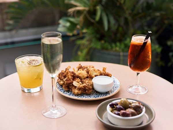 cocktails and food plates at Rooftop at The Sussex Hotel