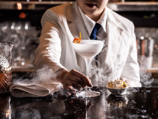 a bartender holding a drink at Zeta Bar