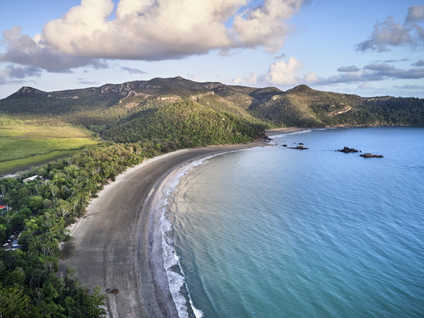Aerial drone image at sunrise over Cape Hillsborough with blue water and green rainforest and nice morning warm sunlight