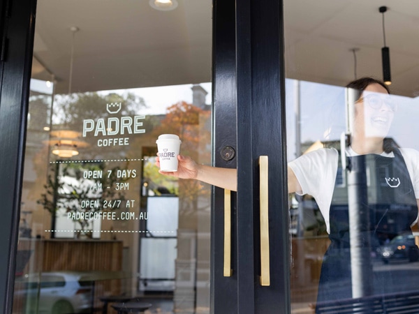 a staff at Padre Paddington handing out a cup of coffee