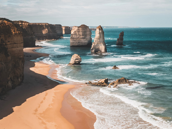 Ocean Rock Formation And Cliffs On Beach Against Sky In Great Ocean Road Australia