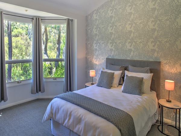 a bedroom with windows at Banksia Cottage, Leura