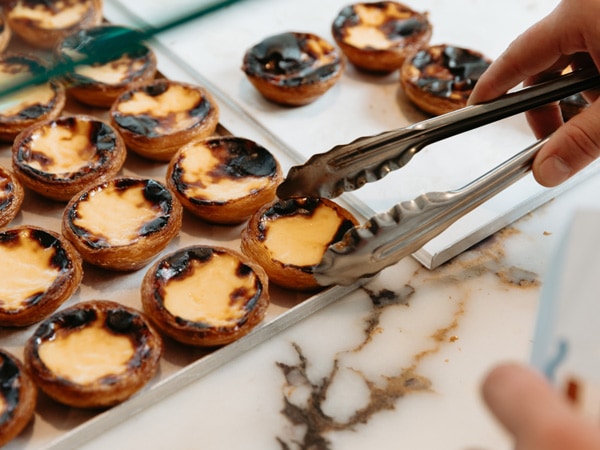 picking up Portuguese tarts using a tong in Casa Nata, Thornbury