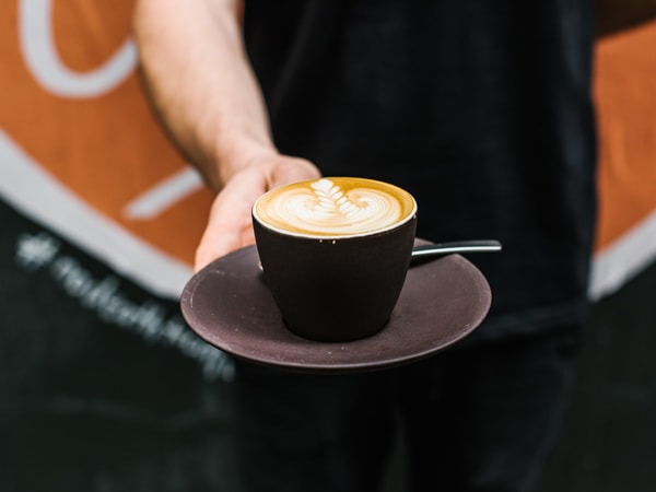 a person holding a cup of coffee at Single O Cafe in Surry Hills