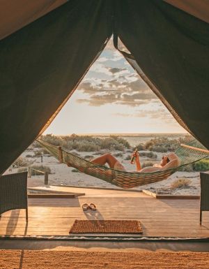 Guest sips a drink in a hammock at Sal Salis as the sun sets