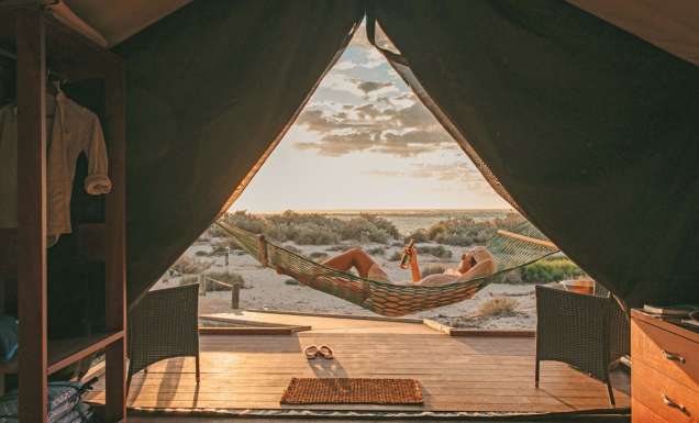 Guest sips a drink in a hammock at Sal Salis as the sun sets