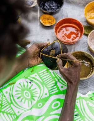 a close-up of a Tiwi artist painting