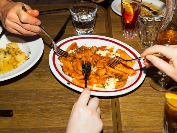 hands getting food on the plate using fork at Studio Amaro