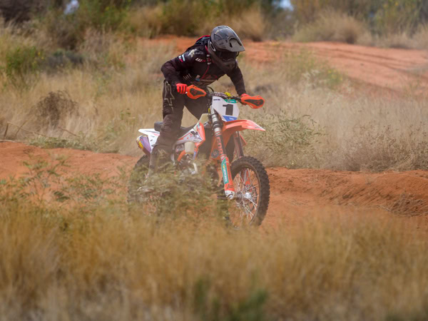 a motorbike rider racing through the desert country during the Tatts Finke Desert Race