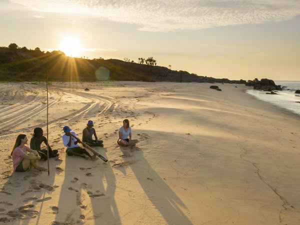 Group sitting on beach at Banubanu Beach Retreat in Arnhem Land