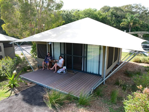a family relaxing outside their glamping tent, Bradbury’s Beach at Minjerribah Camping