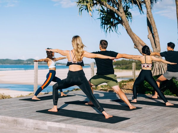 people participating in a yoga class on the beach at First Light Club Beachfront Yoga at Byron Bay, NSW