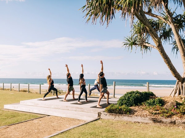 participants stretching their body during the yoga session by the beach at First Light Club Beachfront Yoga at Byron Bay, NSW