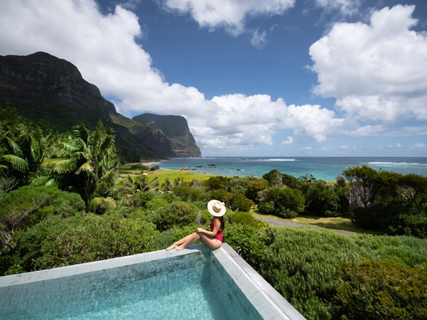 a woman sitting on the edge of the infinity pool on Lord Howe Island at Capella Lodge