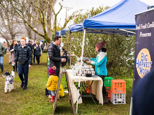a busy market scene with people shopping at stalls along Daylesford Farmer's Market