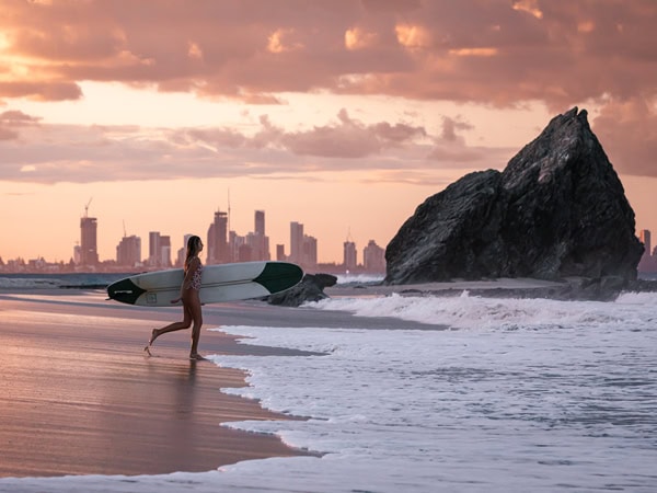 a surfer heading out to surf at sunrise at Elephant Rock, Qld