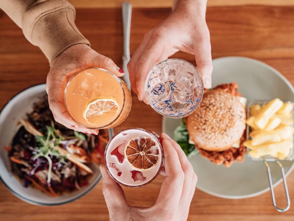 a table-top view of hands holding out drinks at Flinders Food Co