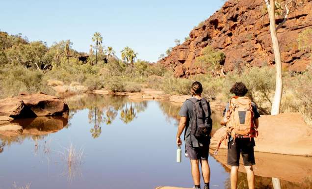 Two men hiking beside Finke River in Finke Gorge National Park