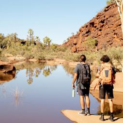 Two men hiking beside Finke River in Finke Gorge National Park