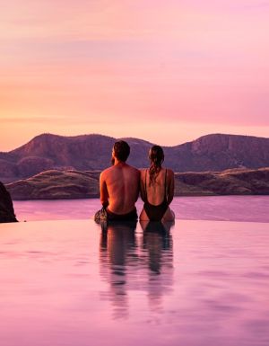 a couple sitting by the edge of the infinity pool during sunset at Lake Argyle Resort, WA