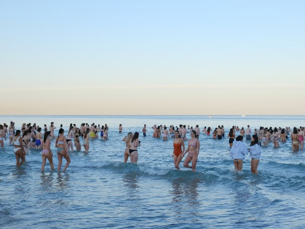 a crowded beach during the Salty Sips Ocean Dip event
