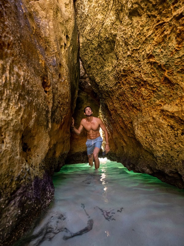 a man squeezing himself in a narrow rock passage at Stokes Bay