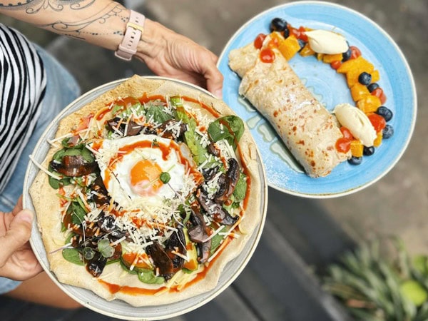 a hand holding two plates of food at The Velo Project