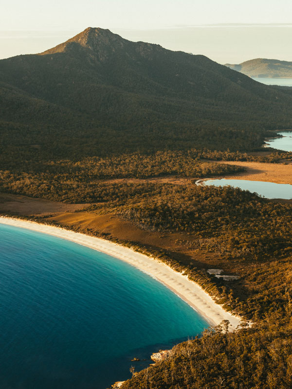 an aerial view of the mountains and white-sand beach at Wineglass Bay