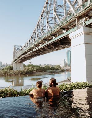 a couple relaxing in the pool by the Brisbane River and Story Bridge at Crystalbrook Vincent, Howard Smith Wharves