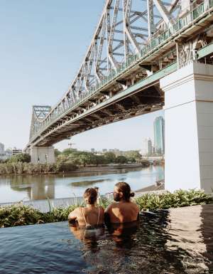 a couple relaxing in the pool by the Brisbane River and Story Bridge at Crystalbrook Vincent, Howard Smith Wharves
