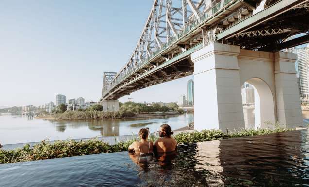 a couple relaxing in the pool by the Brisbane River and Story Bridge at Crystalbrook Vincent, Howard Smith Wharves