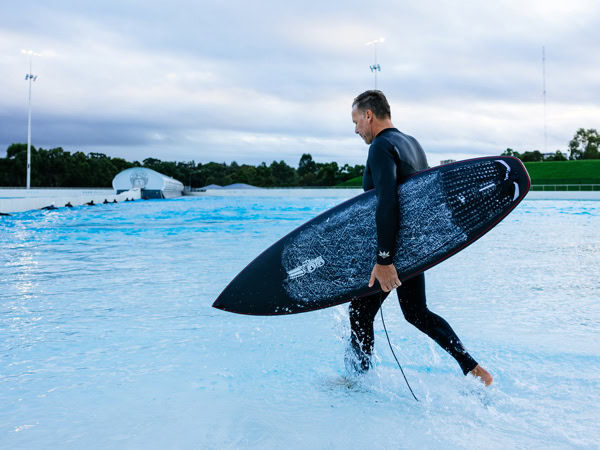 a surfer holding a surfboard at URBNSURF Sydney