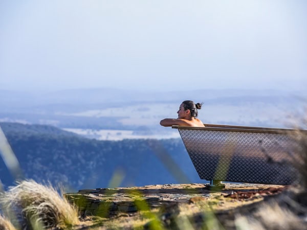 a woman relaxing in the outdoor tub at Bubbletent Australia overlooking the Capertee Valley